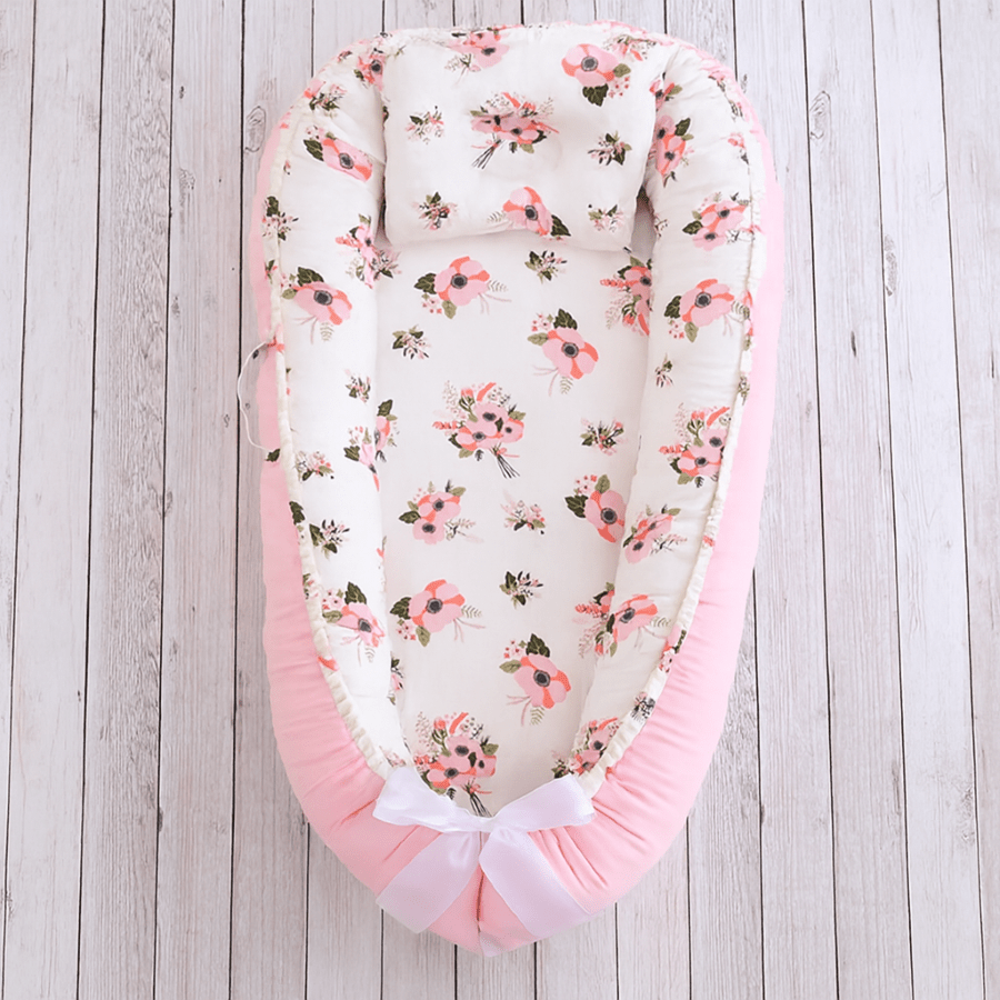 Réducteur de lit évolutif Rosée de Rêve, motif floral pastel, ruban blanc et coussin naissance.