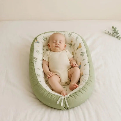 Bébé endormi dans un bébé cocon vert pastel, paisiblement installé sur un lit moelleux.