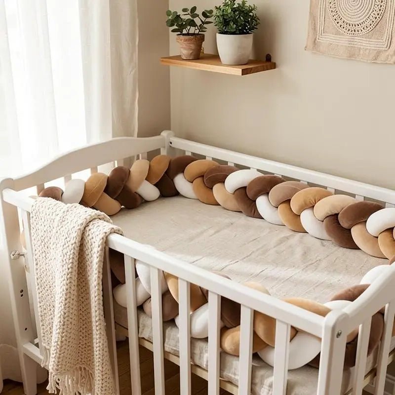 Tresse de lit bébé Caramel™ entourant leberceau blanc, avec couverture crème et décor cocooning dans une chambre lumineuse.