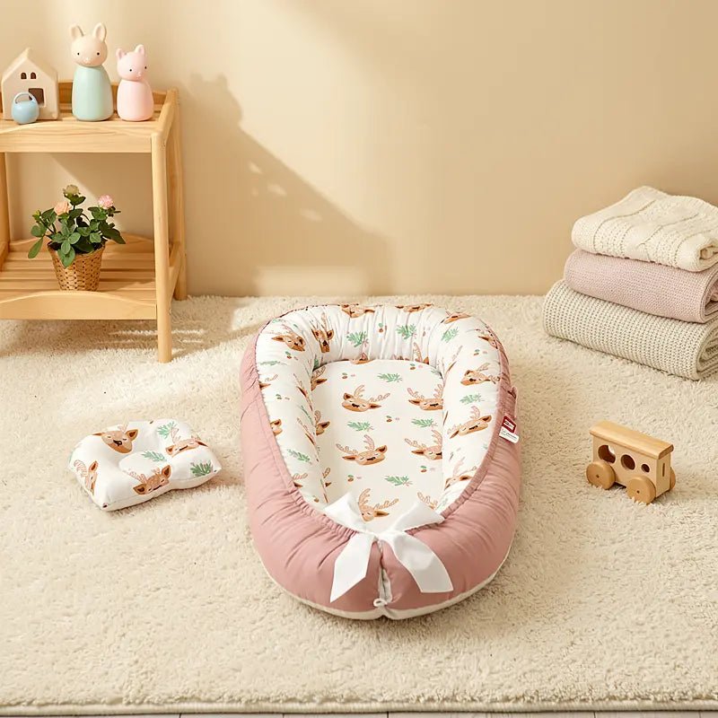 Réducteur de lit bébé rose poudré avec motif cerf, posé sur un tapis crème dans une chambre douce et lumineuse.