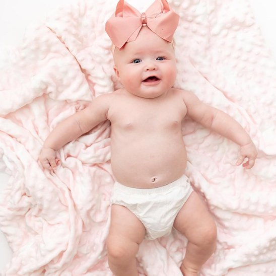 Bébé allongé avec couverture bebe rose douce et grand nœud
