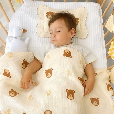 Bébé dormant paisiblement avec couverture bebe crème motifs oursons adorables.