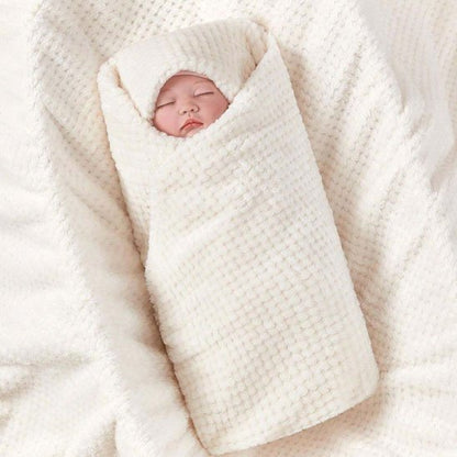 Bébé emmailloté dans une couverture bébé crème douce en coton gaufré texturé.