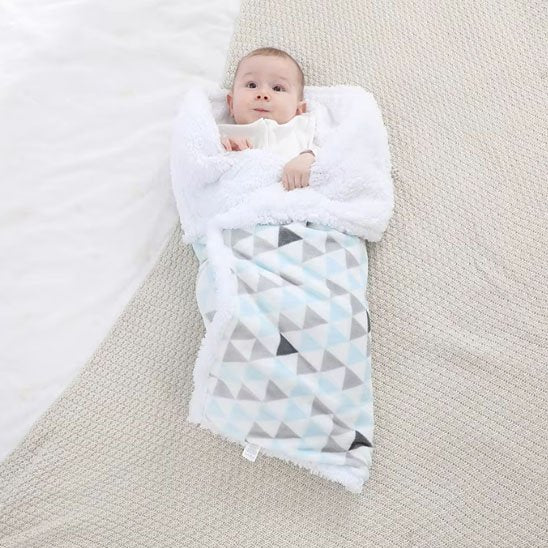 Bébé enveloppé sous couverture bébé géométrique douce bleu gris blanche.