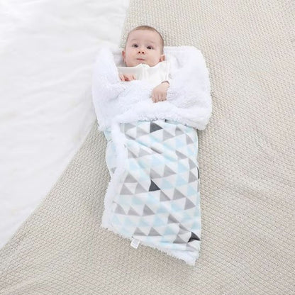 Bébé enveloppé sous couverture bébé géométrique douce bleu gris blanche.