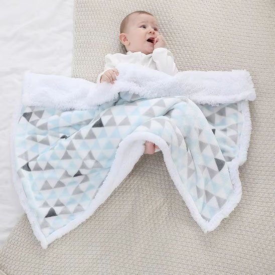 Bébé reposant sous couverture bébé douce géométrique bleu, blanc, gris moelleuse.
