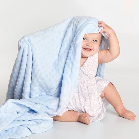 Bébé souriant sous couverture bebe bleue douce en studio
