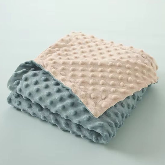 Couverture bébé bleu et beige à texture douce et moelleuse.