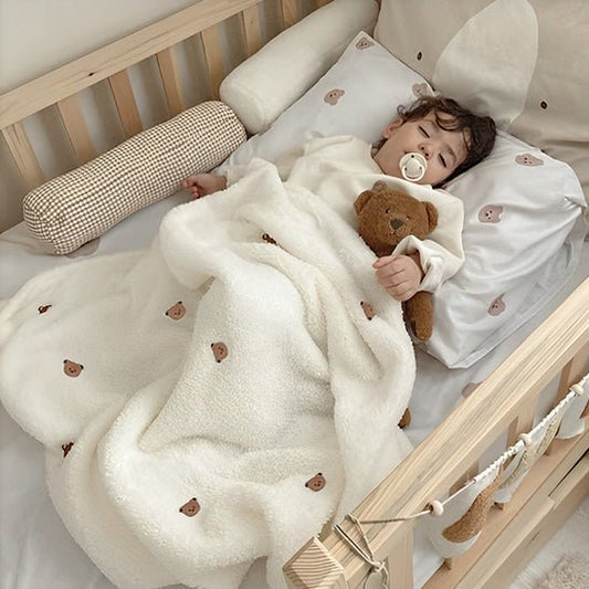 Couverture bebe, motif ours, enfant endormi paisiblement dans son lit en bois.