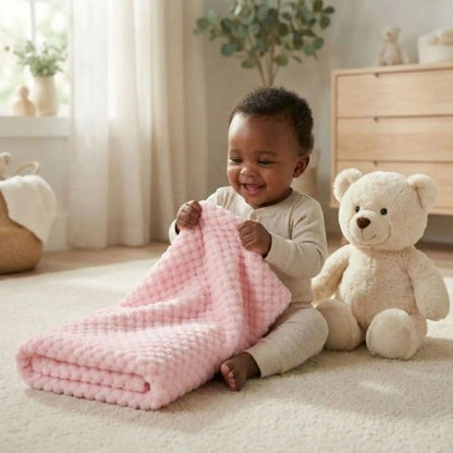 Bébé assis jouant avec couverture bébé rose douce dans chambre chaleureuse.