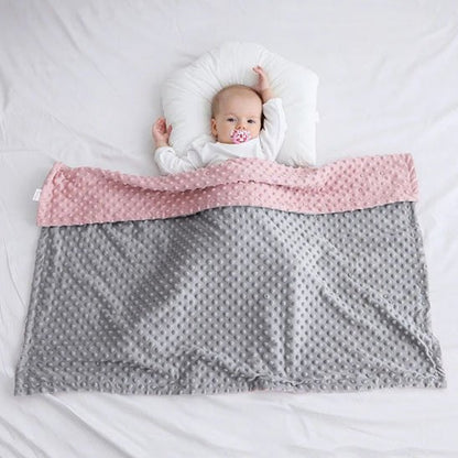 Enfant endormi sous couverture bébé rose et grise à texture douce.