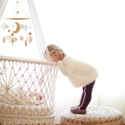 Enfant curieux regardant mobile bebe macrame avec etoiles et lune.