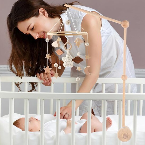 Mobile bébé suspendu au-dessus du berceau, maman regardant tendrement bébé.