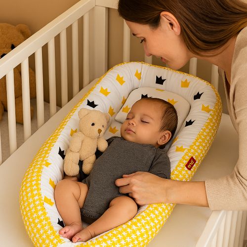 Maman offre toutou à bébé dormant dans réducteur CocoSérénité jaune couronnes berceau blanche