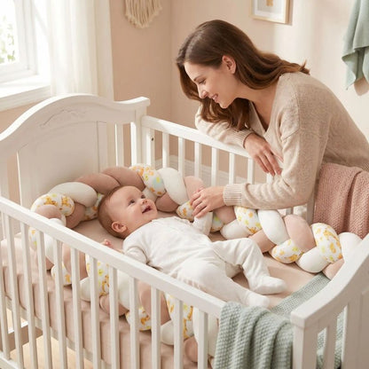Bébé souriant à sa maman dans une berceau blanche avec tour de lit tressé.